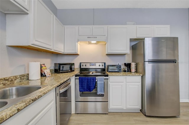 kitchen with light hardwood / wood-style floors, light stone countertops, appliances with stainless steel finishes, white cabinetry, and sink