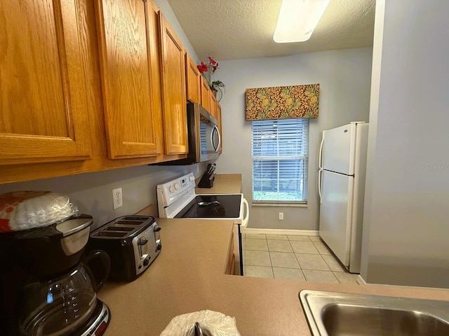 kitchen featuring white appliances, a textured ceiling, and light tile patterned floors