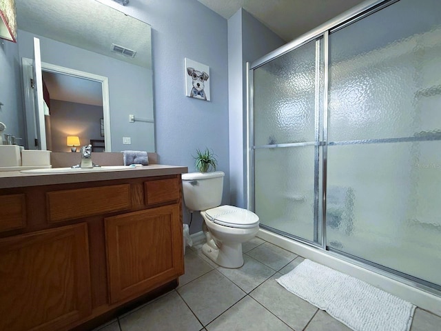 bathroom featuring tile patterned flooring, vanity, a shower with shower door, and toilet