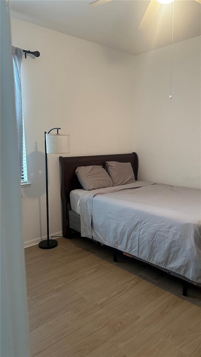 bedroom with hardwood / wood-style floors, multiple windows, and ceiling fan