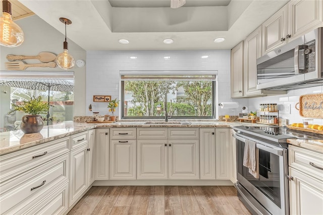 kitchen featuring stainless steel appliances, white cabinetry, hanging light fixtures, and light stone counters