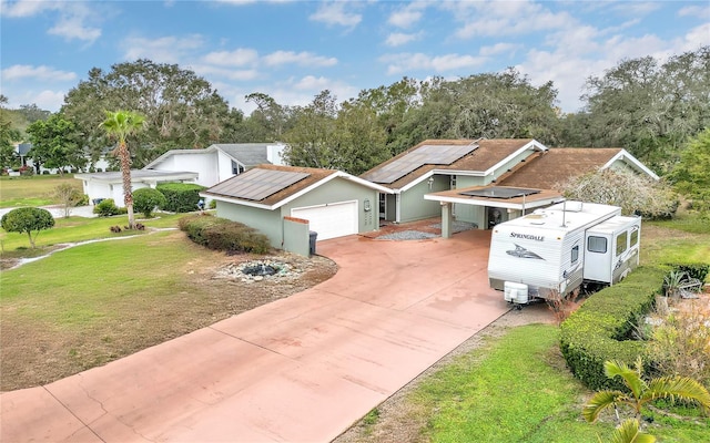 view of front of house featuring a garage, solar panels, and a front lawn