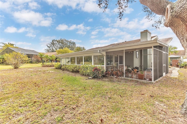 rear view of house featuring a sunroom and a yard