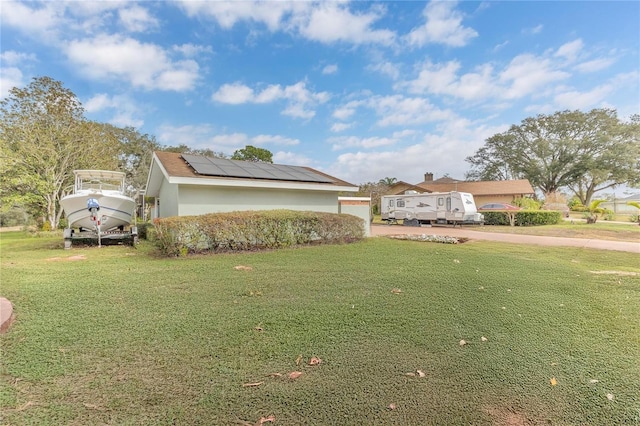 view of side of home featuring a lawn and solar panels