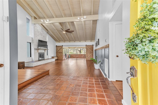 hall featuring beamed ceiling, high vaulted ceiling, tile patterned floors, and a barn door