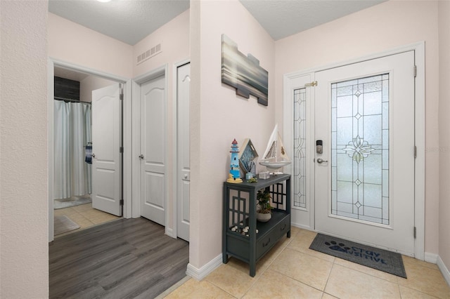 tiled foyer entrance with a textured ceiling