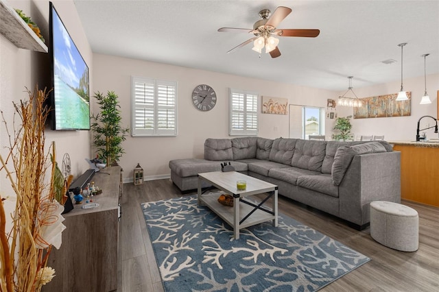 living room with ceiling fan with notable chandelier, sink, and hardwood / wood-style floors