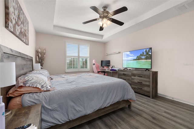 bedroom featuring ceiling fan, a textured ceiling, hardwood / wood-style flooring, and a raised ceiling