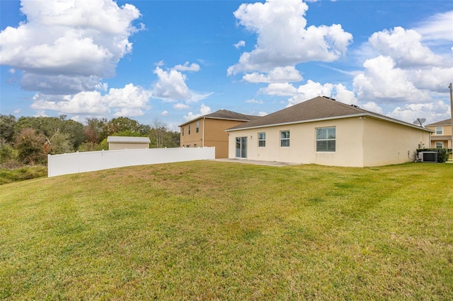 back of house with central AC unit and a lawn