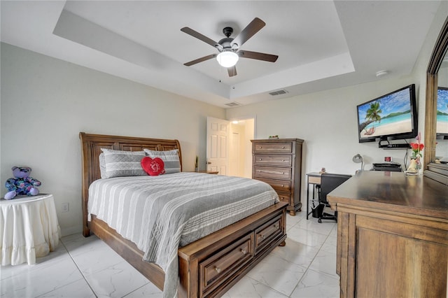 bedroom with ceiling fan and a tray ceiling