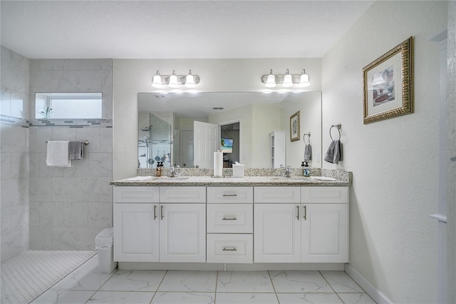 bathroom with tiled shower and vanity