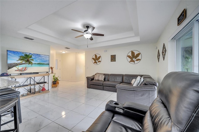 living room featuring ceiling fan and a tray ceiling