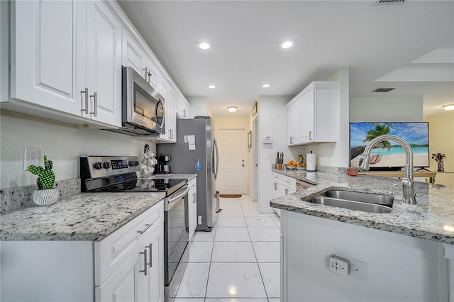 kitchen featuring light stone counters, white cabinets, appliances with stainless steel finishes, and sink