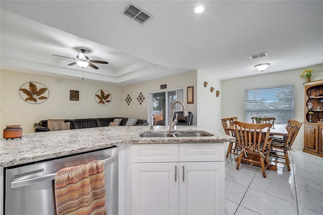 kitchen featuring dishwasher, a raised ceiling, sink, light stone countertops, and white cabinets