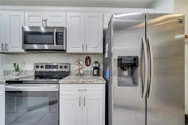 kitchen with stainless steel appliances, white cabinetry, and light stone counters