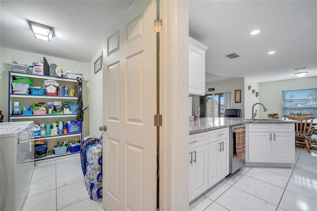 interior space featuring separate washer and dryer, dishwasher, white cabinetry, kitchen peninsula, and light stone counters