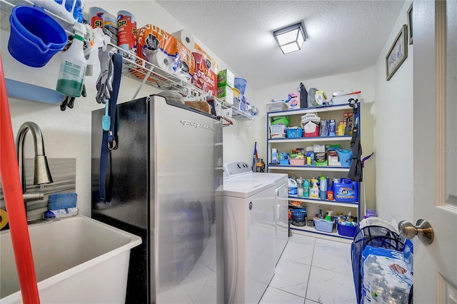 laundry area featuring a textured ceiling, washer and clothes dryer, and sink