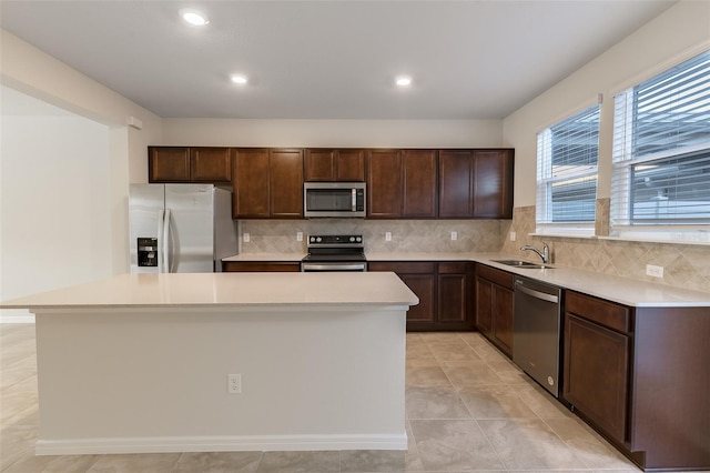 kitchen with sink, tasteful backsplash, light tile patterned floors, appliances with stainless steel finishes, and a kitchen island