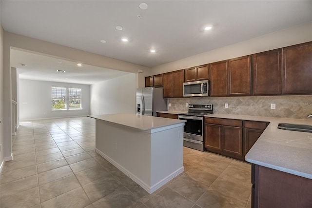 kitchen featuring sink, backsplash, a center island, light tile patterned floors, and stainless steel appliances