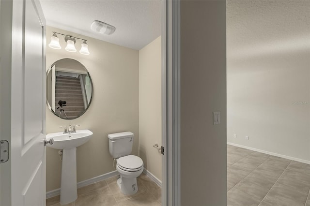 bathroom featuring tile patterned flooring, sink, toilet, and a textured ceiling