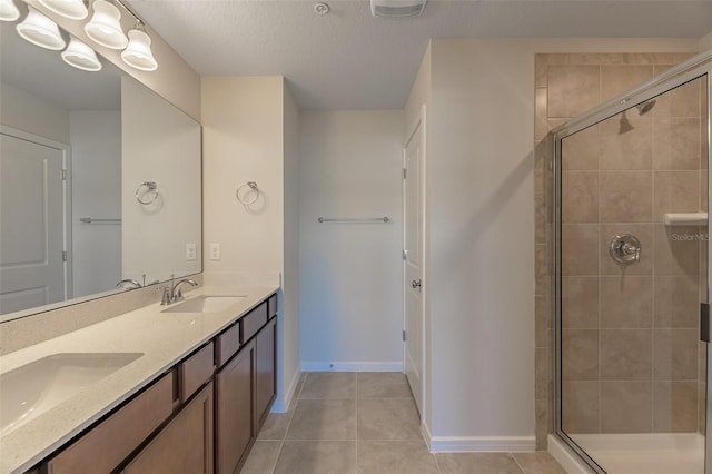 bathroom with tile patterned flooring, vanity, an enclosed shower, and a textured ceiling