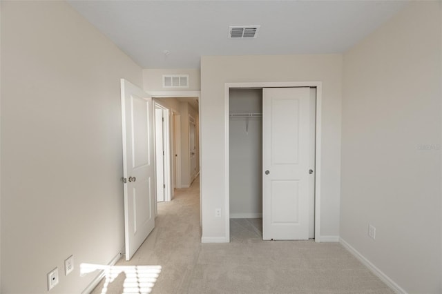 unfurnished bedroom featuring light colored carpet and a closet