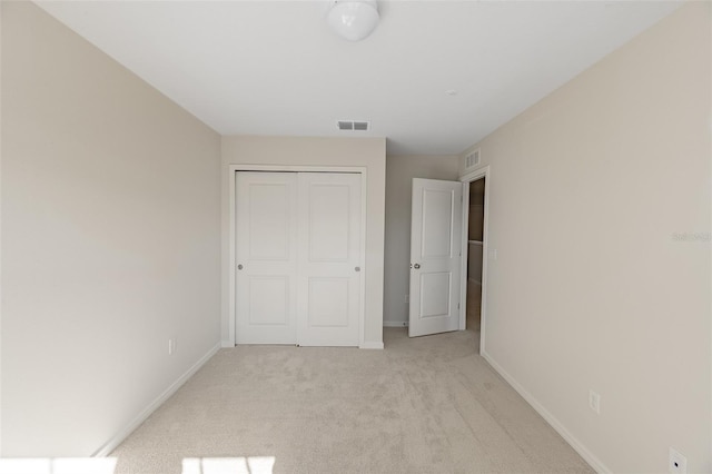 unfurnished bedroom with light carpet and a closet