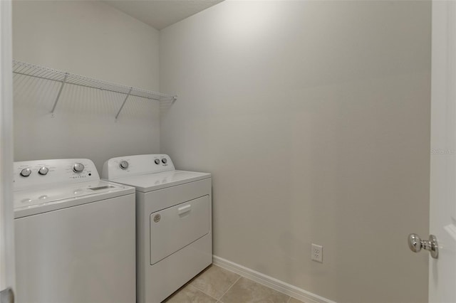 clothes washing area featuring light tile patterned flooring and washer and clothes dryer