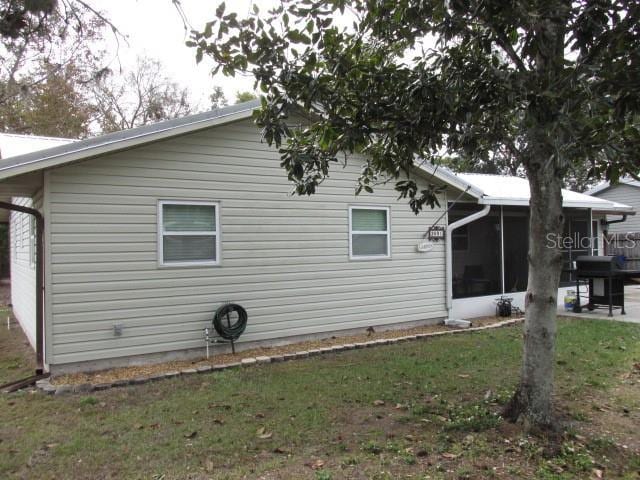 view of home's exterior featuring a sunroom and a lawn