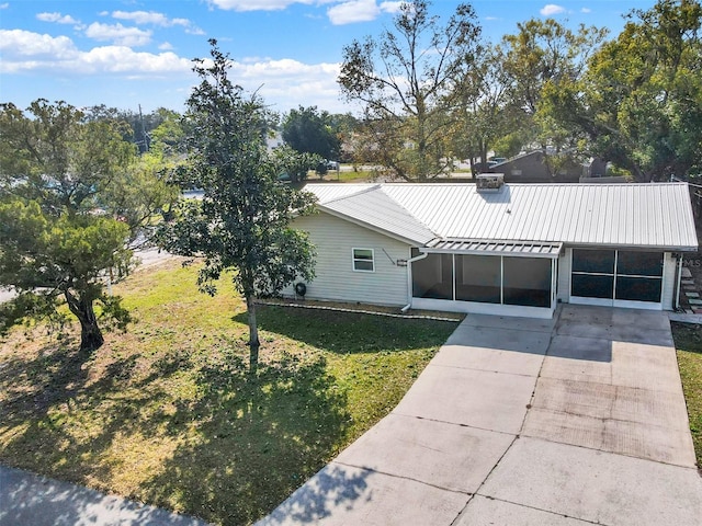 view of front of property with a front lawn, a carport, and a sunroom