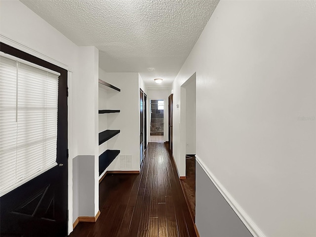 corridor with dark hardwood / wood-style floors and a textured ceiling