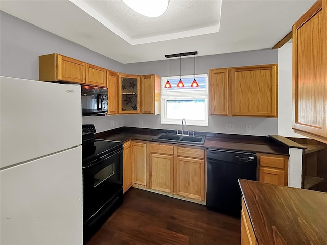 kitchen featuring decorative light fixtures, sink, dark hardwood / wood-style flooring, black appliances, and a raised ceiling