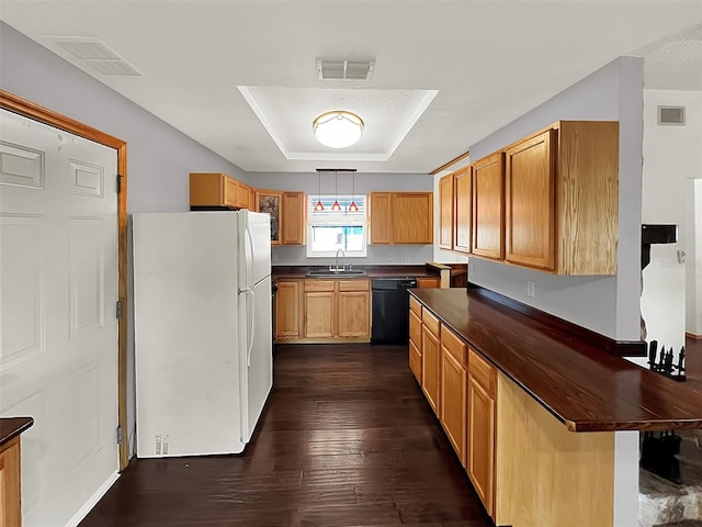 kitchen with sink, black dishwasher, white refrigerator, dark hardwood / wood-style flooring, and a raised ceiling