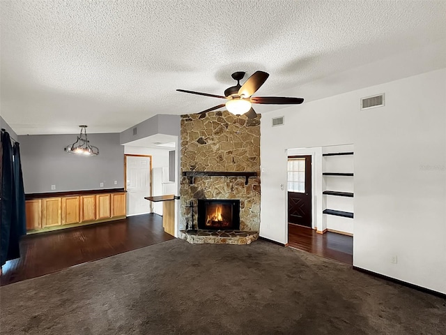 unfurnished living room featuring ceiling fan, a textured ceiling, a fireplace, and dark carpet