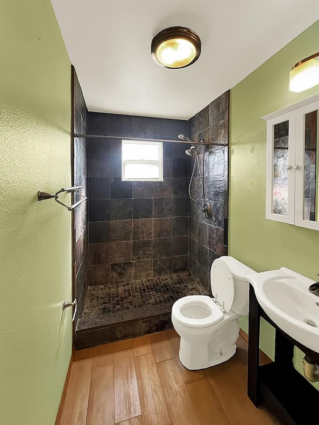 bathroom featuring tiled shower, hardwood / wood-style floors, and toilet