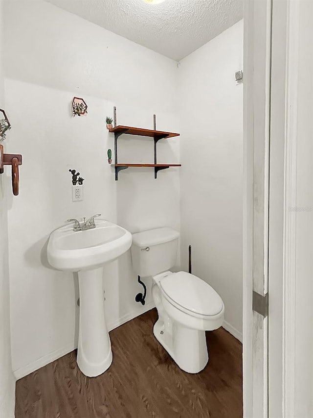 bathroom with toilet, hardwood / wood-style floors, and a textured ceiling