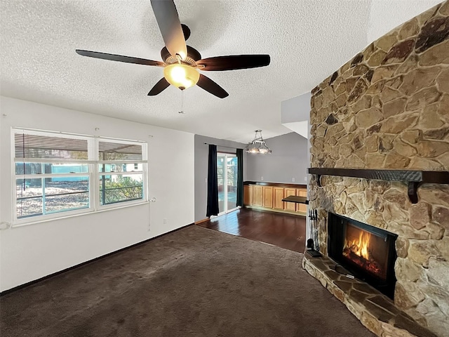 unfurnished living room with vaulted ceiling, a stone fireplace, carpet flooring, ceiling fan, and a textured ceiling