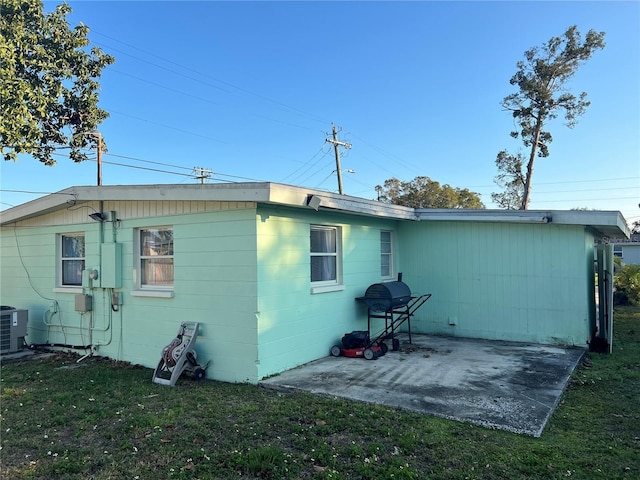 rear view of property with central AC unit, a patio area, and a yard