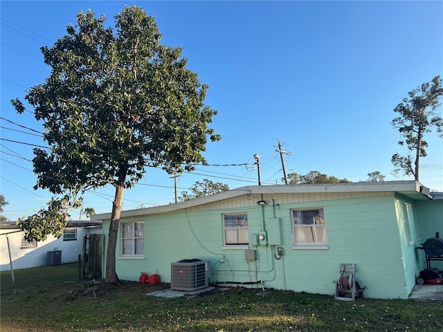 back of house featuring a lawn and central air condition unit