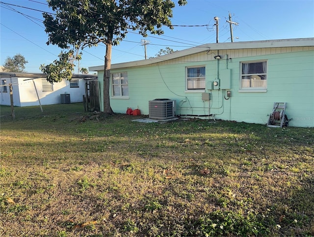 rear view of property featuring a yard and central AC