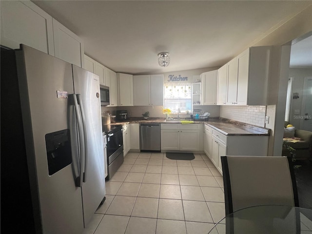 kitchen with decorative backsplash, sink, light tile patterned floors, stainless steel appliances, and white cabinets