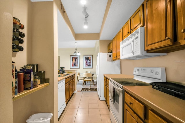 kitchen with white appliances, rail lighting, sink, hanging light fixtures, and light tile patterned floors