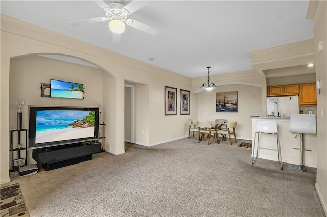 carpeted living room with ceiling fan and ornamental molding