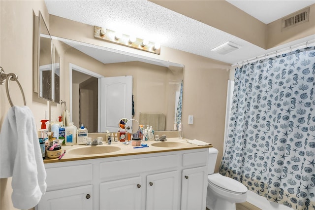 bathroom featuring toilet, vanity, walk in shower, and a textured ceiling