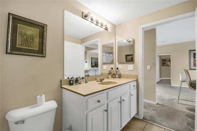 bathroom featuring toilet, vanity, tile patterned flooring, and a textured ceiling