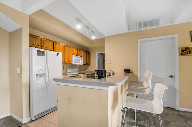 kitchen featuring light tile patterned floors, kitchen peninsula, white appliances, and a kitchen bar