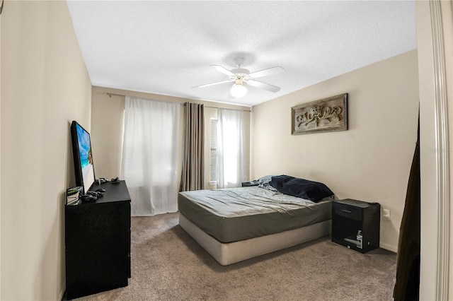 bedroom with ceiling fan, light colored carpet, and a textured ceiling