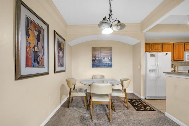 tiled dining area with an inviting chandelier and ornamental molding