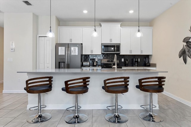 kitchen with appliances with stainless steel finishes, sink, an island with sink, and hanging light fixtures