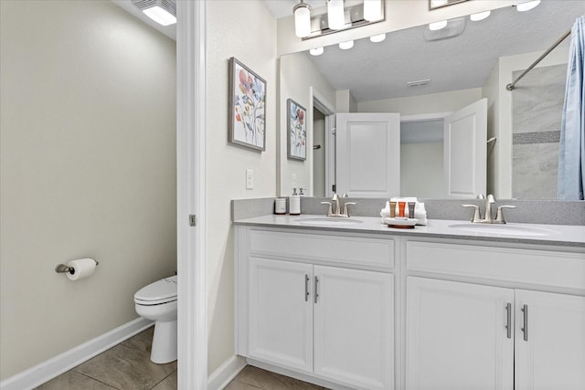 bathroom with tile patterned flooring, vanity, a textured ceiling, and toilet